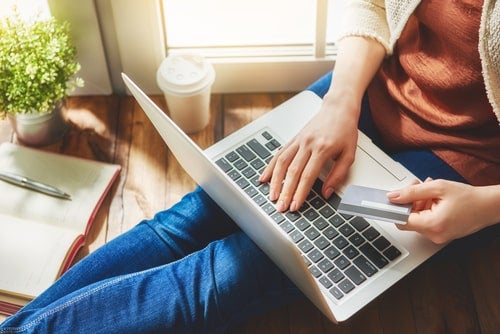 Cropped shot of male hands holding a credit card whilst online shopping on his laptop