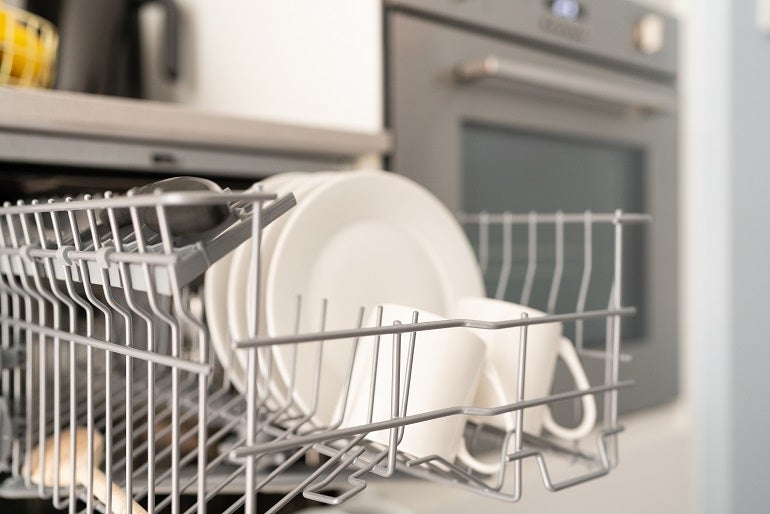 Cropped shot of white plates and mugs in the dishwasher