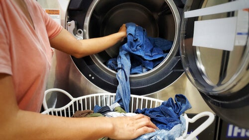 Cropped shot of female hands loading jeans in to a tumble dryer