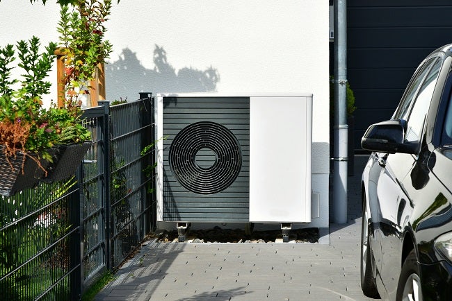 Cropped shot of air-source heat pump on a driveway next to a black car