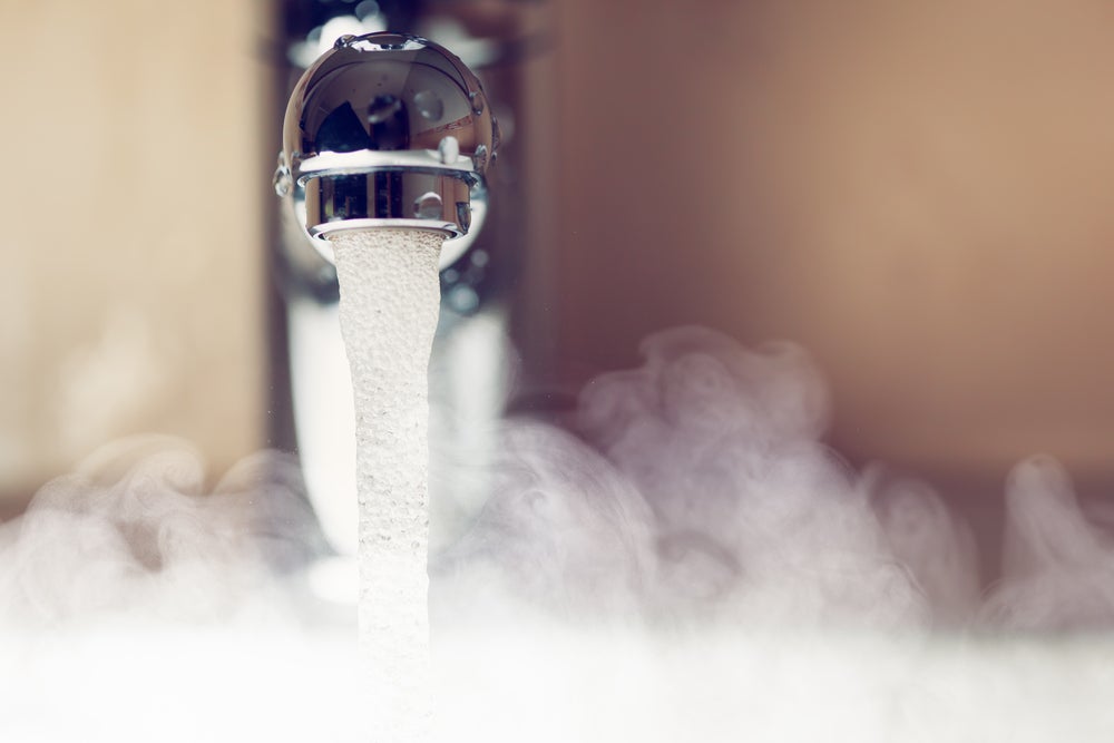 Cropped shot of boiling water running from a silver metal tap