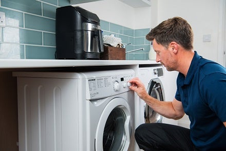 Domestic and general engineer repairing a washing machine